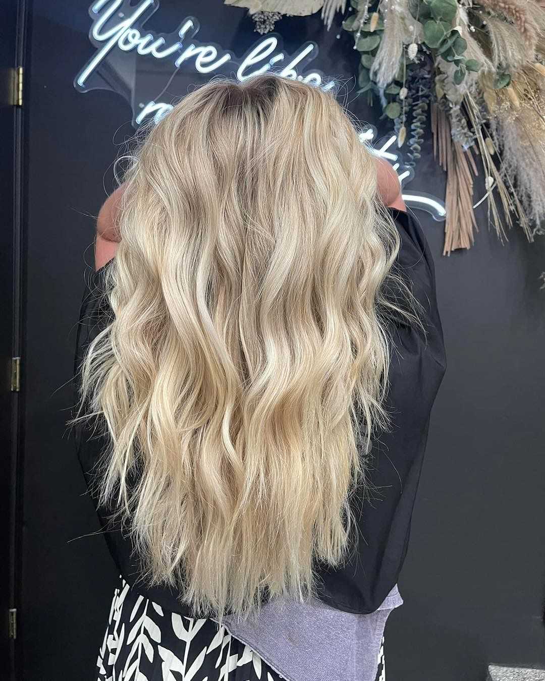 Blonde wavy hairstyle showcased against a dark backdrop with text decor.